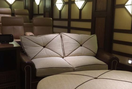 Custom-home-theatre-leather-ottoman-oval-nail-head-trim-stained-tapered-legs-curved-pillow-back-love-seat-upholstered-wall-panels